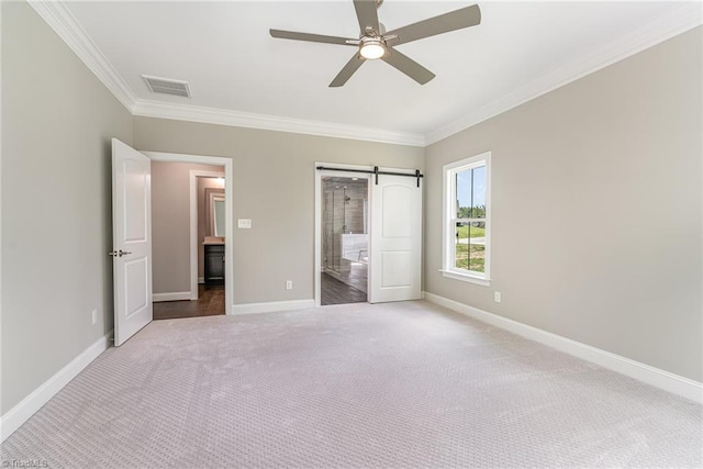 unfurnished bedroom with a barn door, baseboards, and crown molding