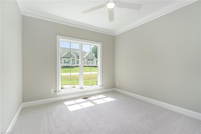 carpeted spare room with baseboards, a ceiling fan, visible vents, and crown molding