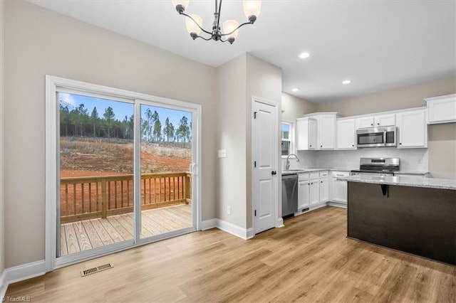 kitchen featuring pendant lighting, sink, white cabinetry, stainless steel appliances, and light stone countertops