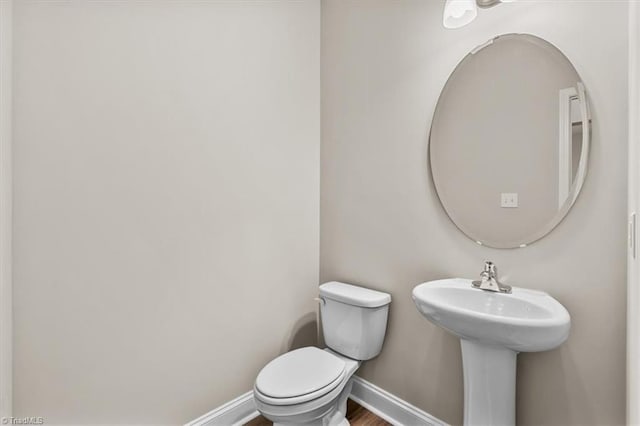 bathroom with wood-type flooring, toilet, and sink