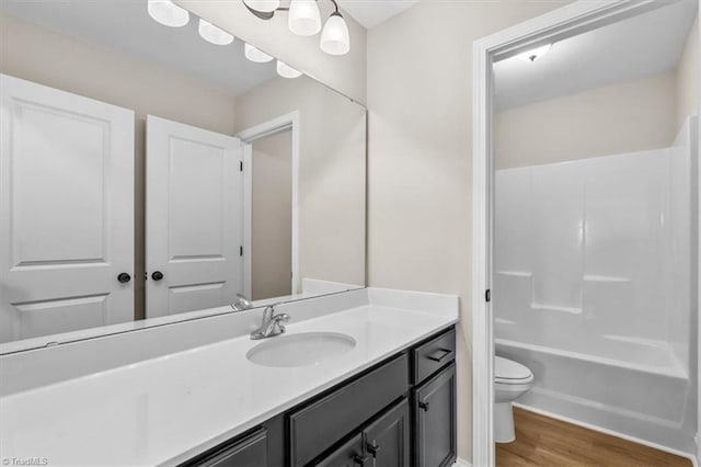 full bathroom featuring vanity, hardwood / wood-style floors, shower / bathtub combination, and toilet