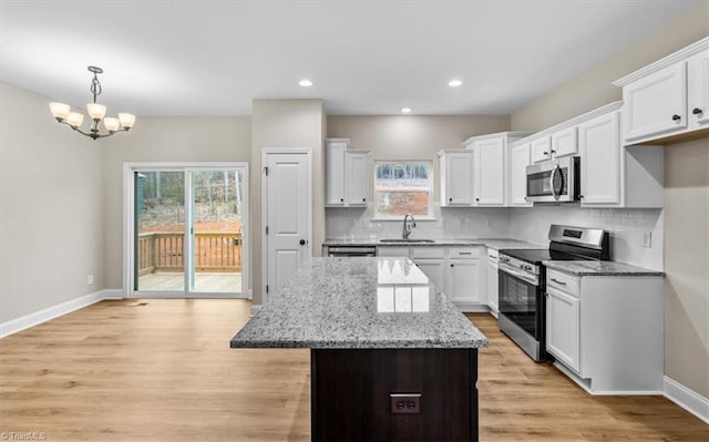 kitchen featuring sink, white cabinetry, a center island, stainless steel appliances, and light stone countertops