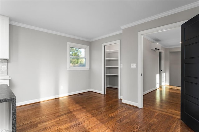 unfurnished living room featuring ornamental molding, dark wood-style flooring, a wall unit AC, and baseboards