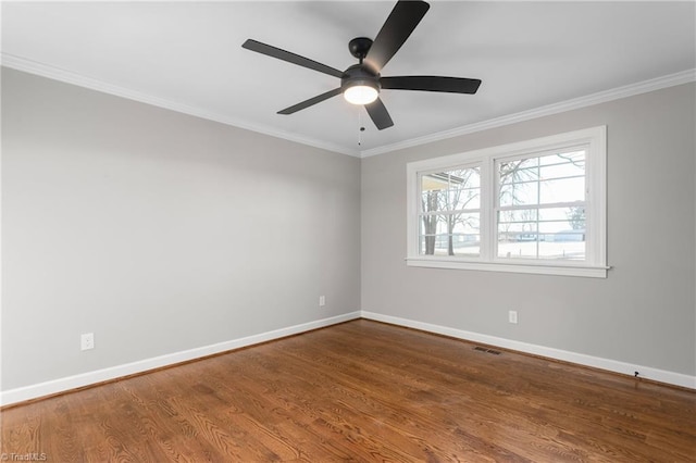 spare room with crown molding, wood finished floors, visible vents, and baseboards