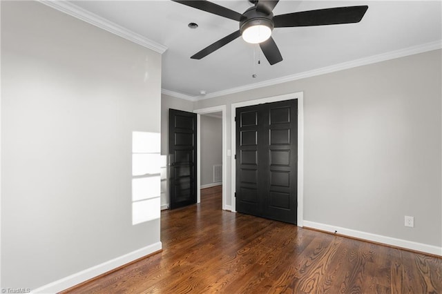 unfurnished bedroom featuring wood finished floors, a ceiling fan, baseboards, visible vents, and crown molding