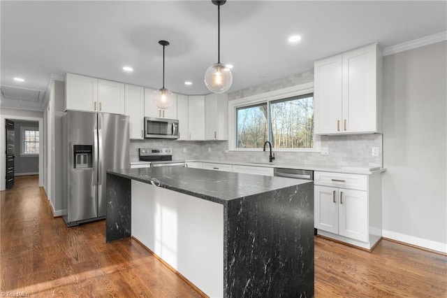 kitchen featuring dark wood-style floors, appliances with stainless steel finishes, a kitchen island, and a sink