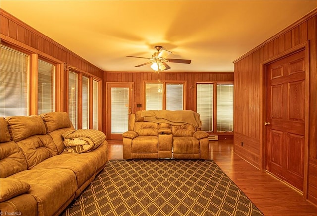 living room featuring ceiling fan, wood-type flooring, and wood walls