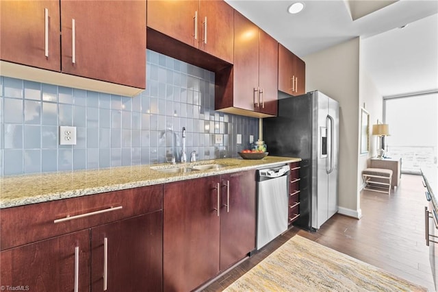 kitchen featuring backsplash, sink, dark hardwood / wood-style floors, appliances with stainless steel finishes, and light stone counters