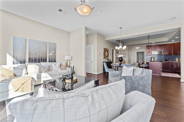 living room with dark hardwood / wood-style floors and an inviting chandelier