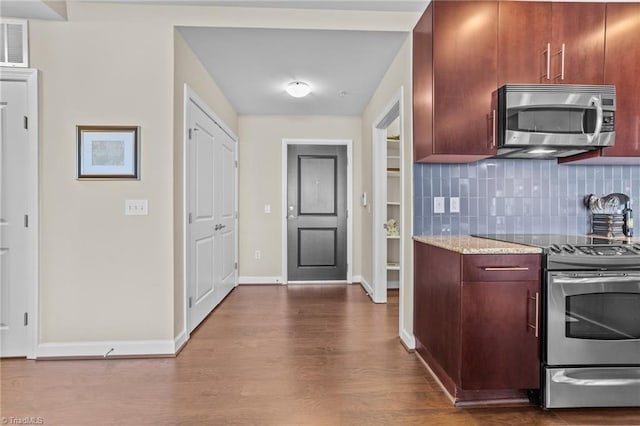 kitchen featuring tasteful backsplash, stainless steel appliances, light stone counters, and hardwood / wood-style flooring