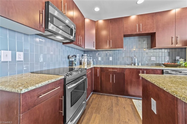 kitchen with decorative backsplash, hardwood / wood-style flooring, light stone counters, and appliances with stainless steel finishes