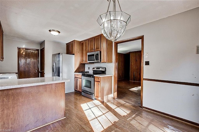 kitchen featuring an inviting chandelier, hardwood / wood-style flooring, light countertops, and stainless steel appliances