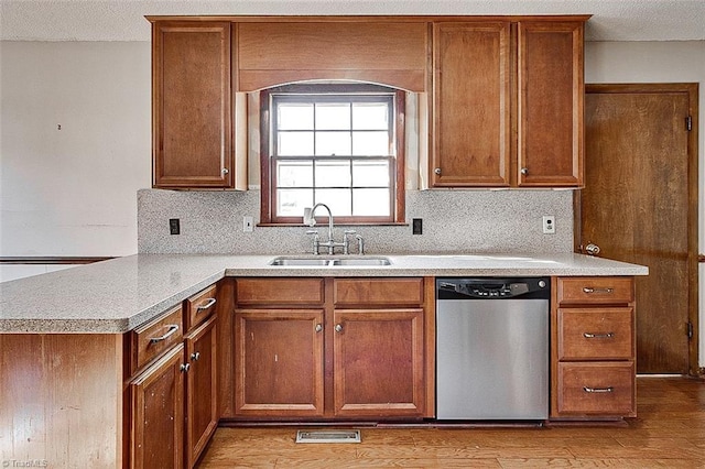 kitchen featuring a sink, light wood-style floors, stainless steel dishwasher, and light countertops