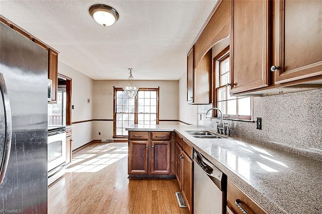 kitchen featuring plenty of natural light, brown cabinetry, appliances with stainless steel finishes, and a sink