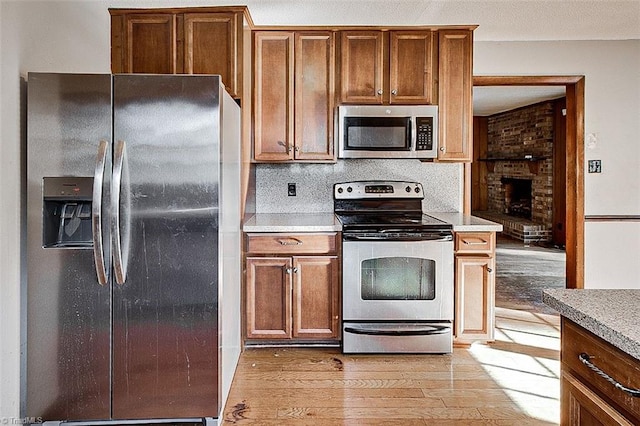 kitchen featuring light wood-type flooring, brown cabinets, appliances with stainless steel finishes, and light countertops