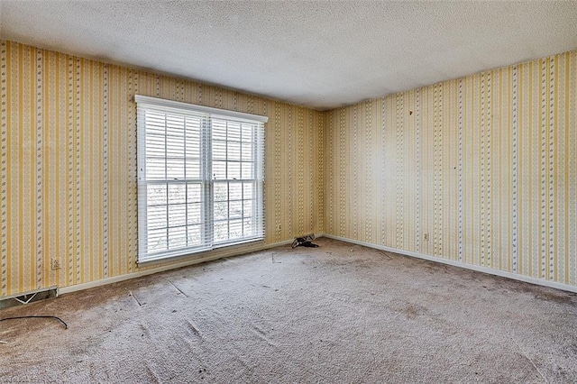 unfurnished room with wallpapered walls, baseboards, carpet floors, and a textured ceiling