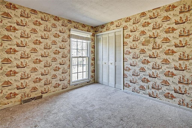 spare room featuring a textured ceiling, visible vents, carpet, and wallpapered walls