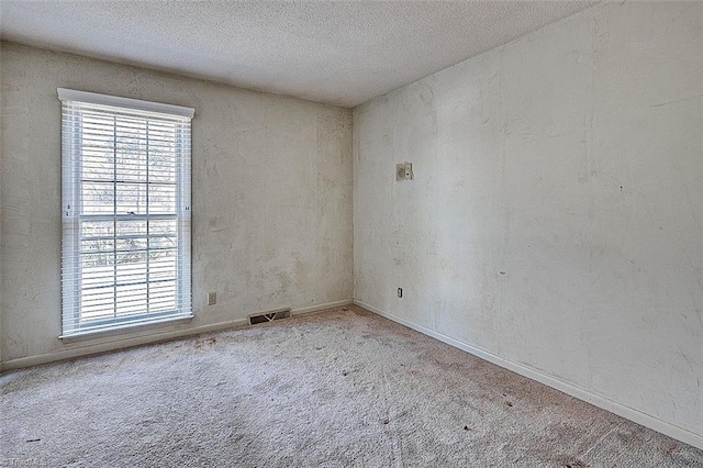 unfurnished room featuring visible vents, baseboards, carpet, and a textured ceiling