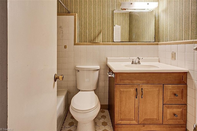 full bathroom with vanity, toilet, wainscoting, and wallpapered walls