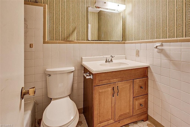 bathroom with wallpapered walls, toilet, and wainscoting