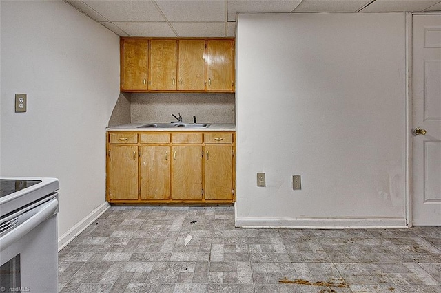 kitchen featuring baseboards, white electric stove, a sink, light countertops, and a paneled ceiling