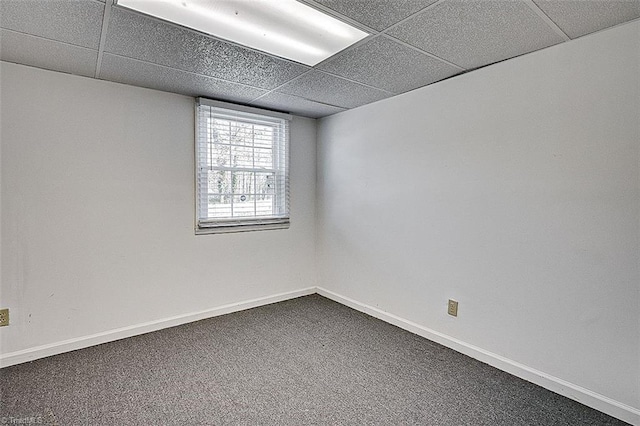 spare room with dark colored carpet, baseboards, and a paneled ceiling