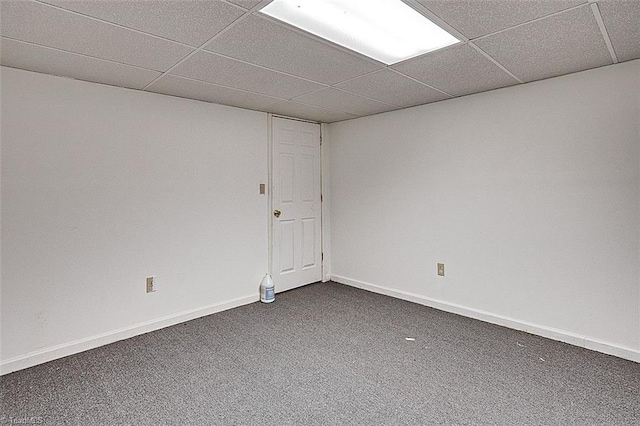 spare room with dark carpet, a paneled ceiling, and baseboards