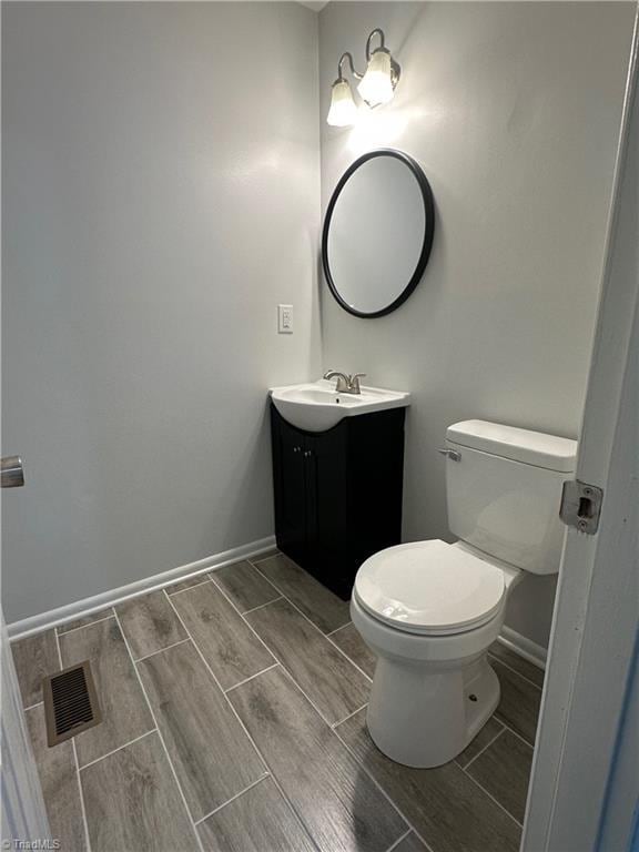1230 W Sedgefield Dr, Winston-Salem, NC 27107 - bathroom with vanity, wood finish floors, toilet, and baseboards