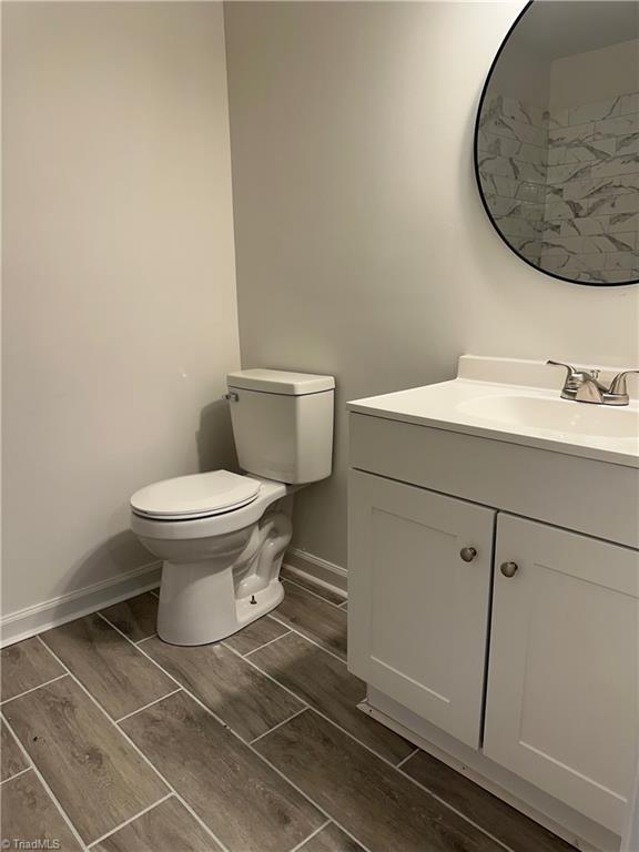 1230 W Sedgefield Dr, Winston-Salem, NC 27107 - bathroom with vanity, wood finish floors, toilet, and baseboards