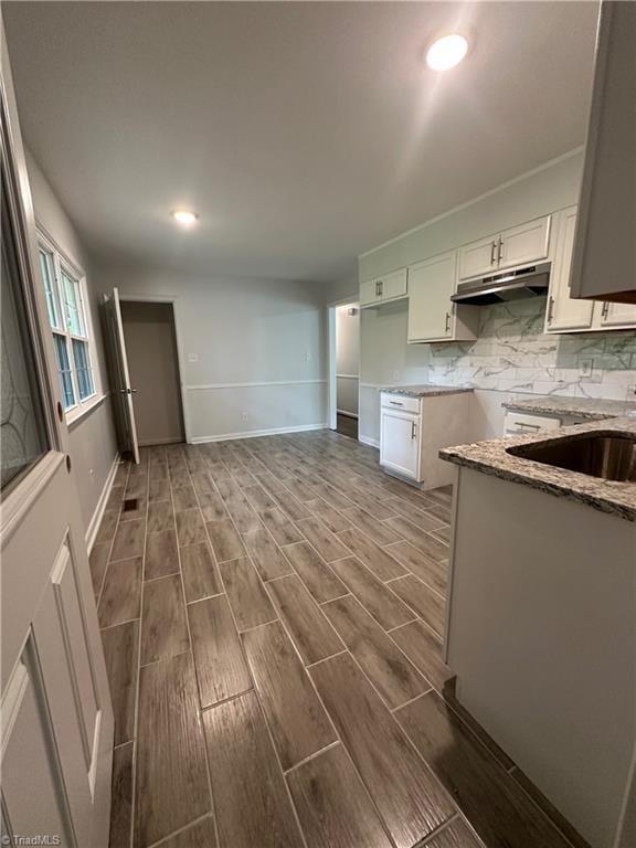 1230 W Sedgefield Dr, Winston-Salem, NC 27107 - kitchen featuring wood finish floors, light stone countertops, under cabinet range hood, baseboards, and decorative backsplash
