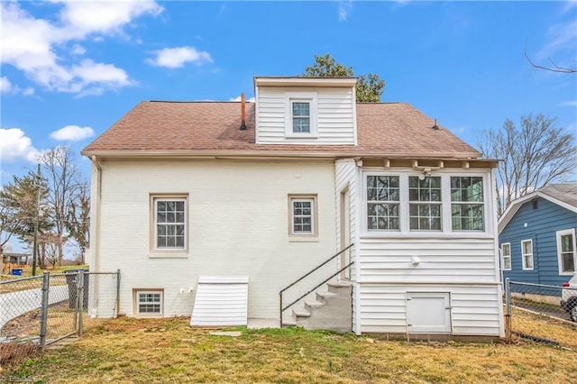 back of house featuring a yard, entry steps, a shingled roof, and fence