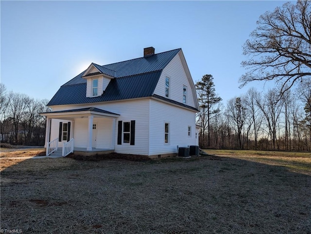 view of front facade featuring a porch, a front yard, and central AC