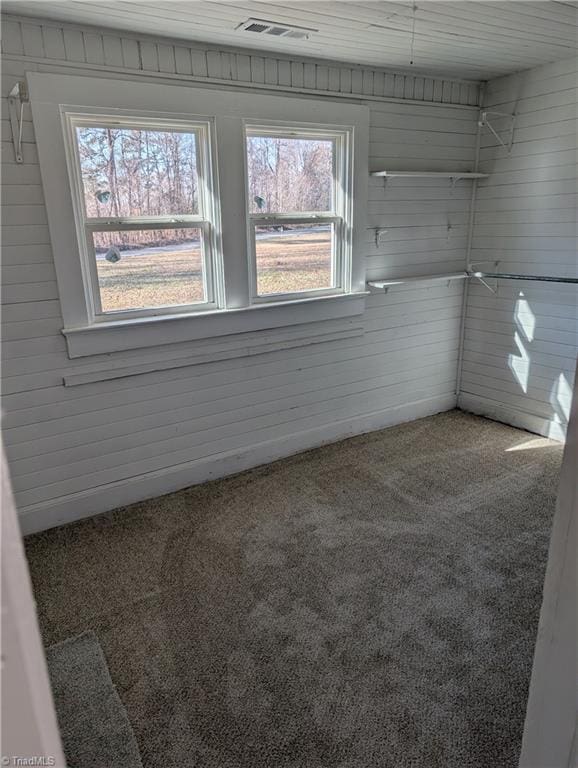 unfurnished room featuring carpet floors and wooden walls