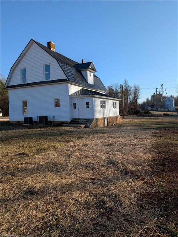 rear view of property with a lawn and central AC unit