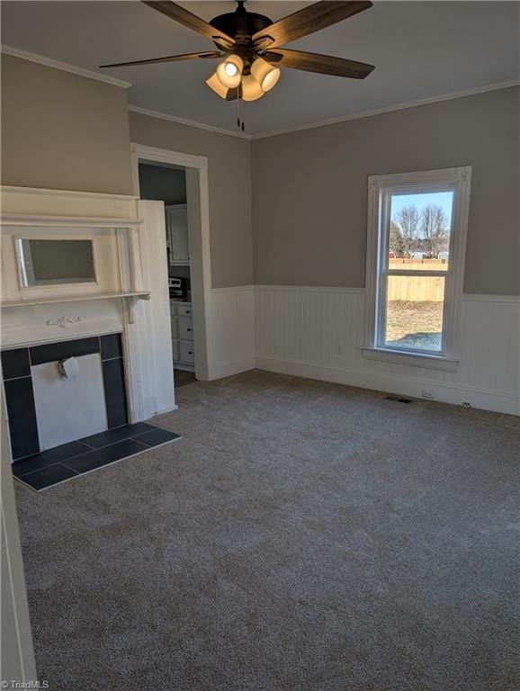 unfurnished living room with carpet, ceiling fan, and crown molding