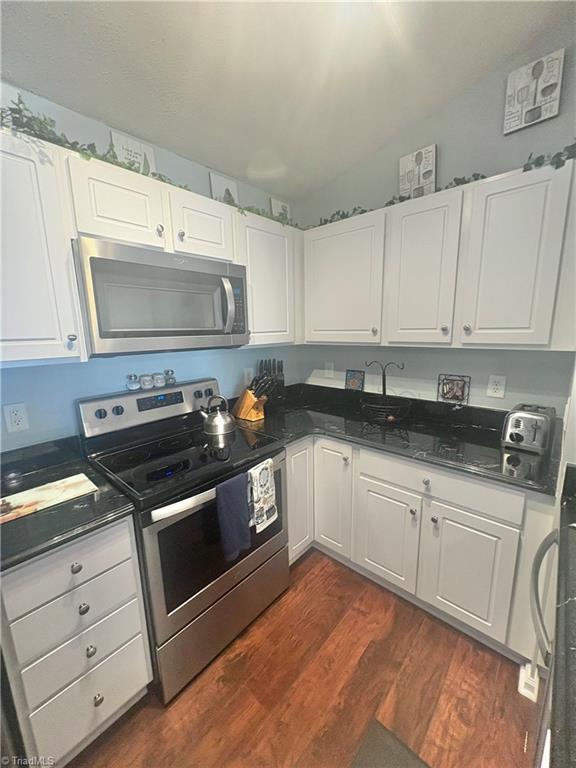 1620 Cherry Blossom Ln Unit 301, Winston-Salem, NC 27127 - kitchen featuring stainless steel appliances, dark wood-style flooring, white cabinetry, and dark countertops