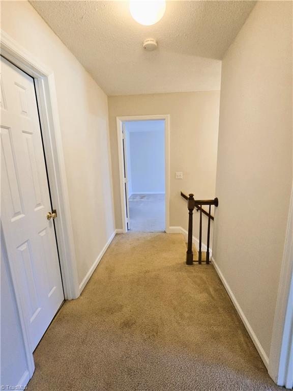 hallway featuring carpet flooring and a textured ceiling