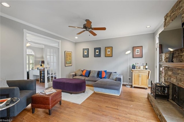 living room with light wood-style floors, a fireplace, and crown molding