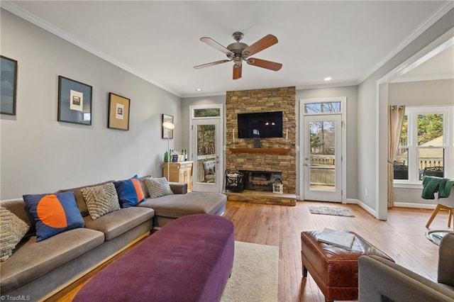 living room with baseboards, a stone fireplace, wood finished floors, and crown molding