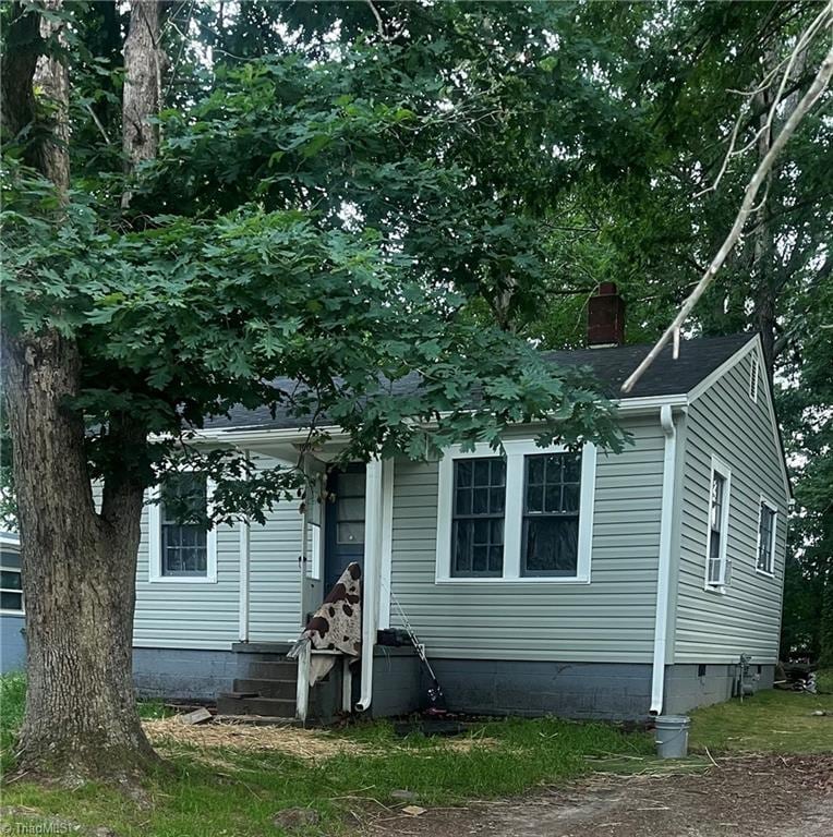 view of front of home with a chimney and crawl space