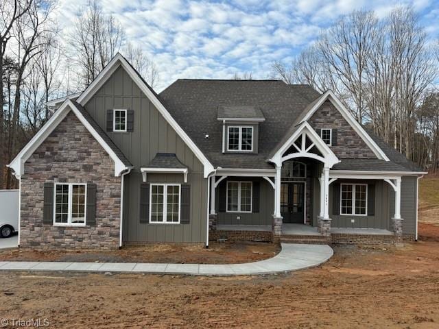 7621 Pemberley Dr, Oak Ridge, NC 27310 - craftsman-style house featuring stone siding, board and batten siding, a porch, and a shingled roof