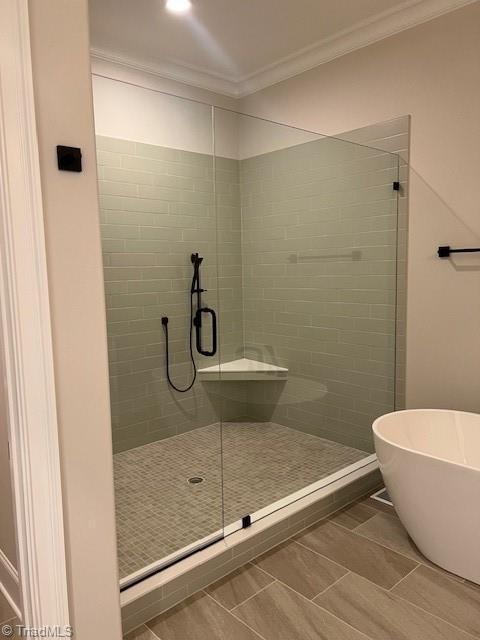 bathroom featuring crown molding and separate shower and tub