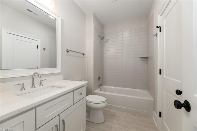 full bathroom with tiled shower / bath, vanity, and toilet