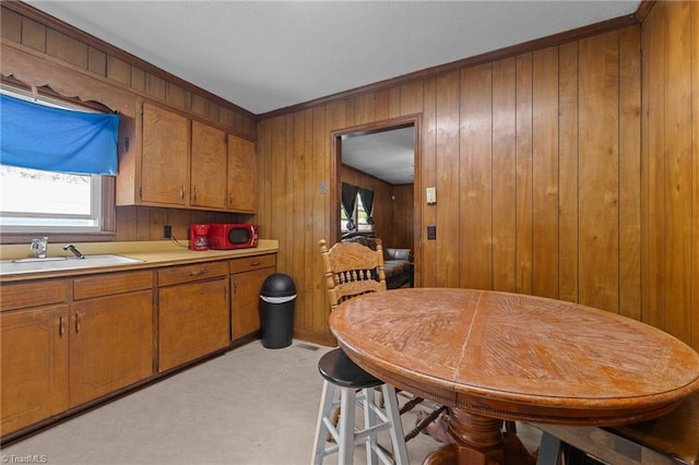 kitchen with a wealth of natural light, a sink, light colored carpet, brown cabinetry, and light countertops