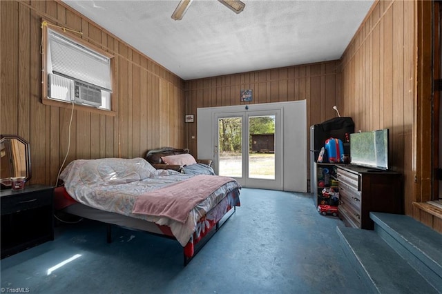 bedroom with concrete flooring, wooden walls, access to exterior, and a ceiling fan
