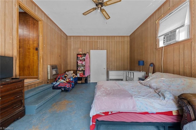 bedroom with cooling unit, heating unit, wood walls, concrete floors, and a ceiling fan