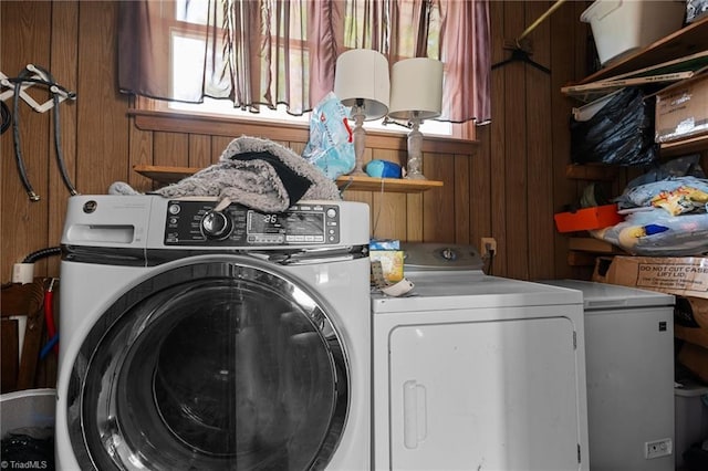 washroom featuring wooden walls, washing machine and clothes dryer, and laundry area