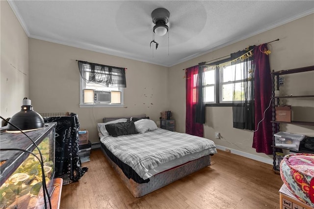 bedroom with ornamental molding, cooling unit, baseboards, hardwood / wood-style flooring, and ceiling fan