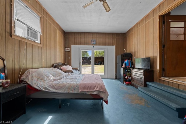 bedroom with concrete floors, a ceiling fan, a textured ceiling, and wooden walls