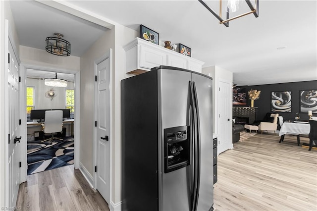 kitchen with white cabinetry, a chandelier, stainless steel fridge, and light wood-style flooring
